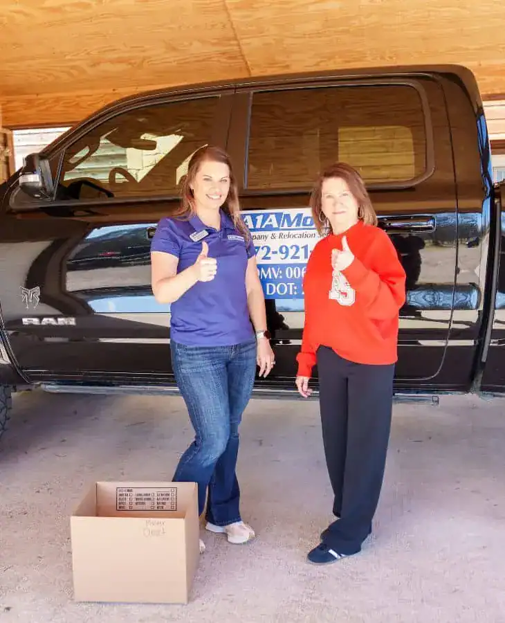 A1A team member and a customer giving a thumbs up next to a moving box