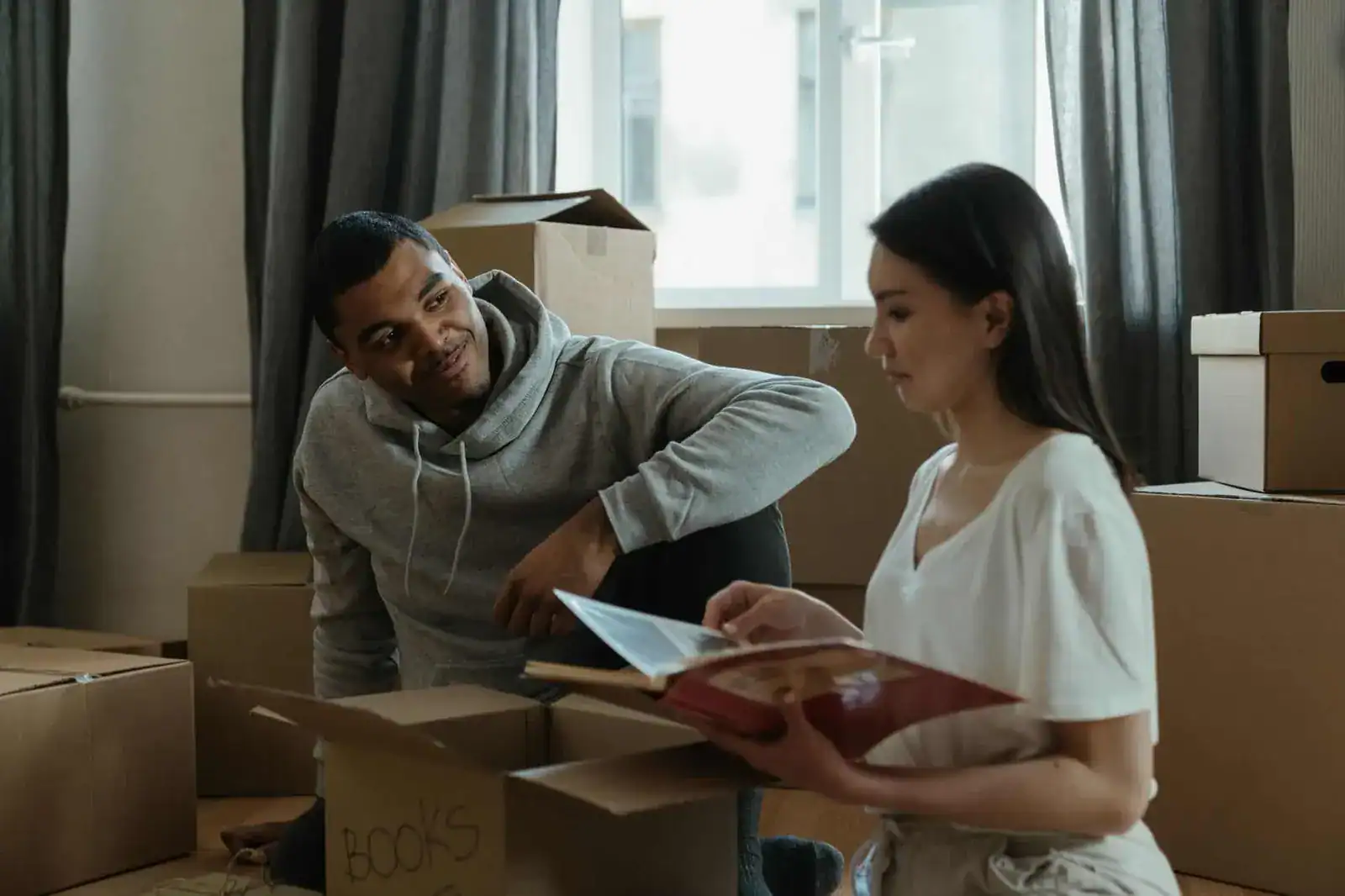 Couple sitting among moving boxes looking through a book