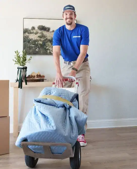 Smiling A1A mover pushing a padded item on a dolly