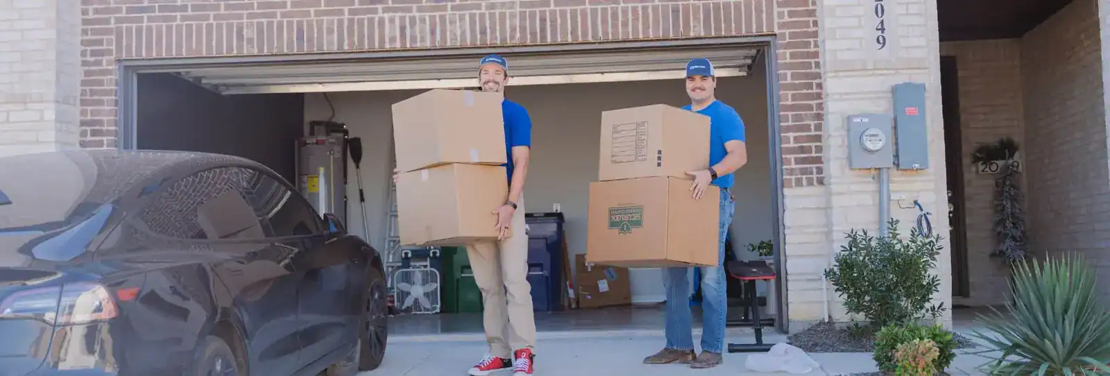 Two A1A movers carrying boxes out of a garage