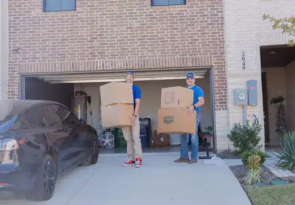 Two A1A movers carrying boxes out of a home's garage