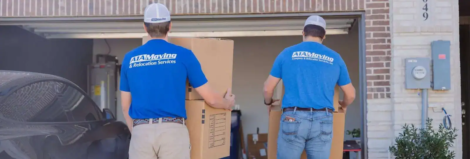Two A1A movers holding moving boxes in a garage