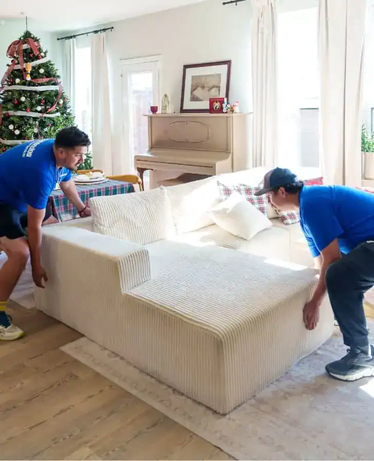 Two A1A movers lifting a sectional sofa in a living room