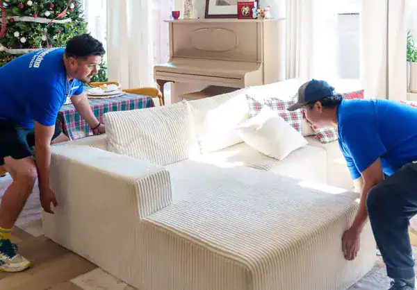 Two A1A movers lifting a white sectional sofa in a living room